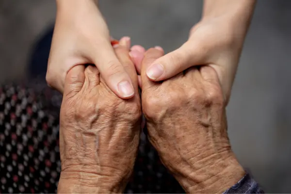 A pair of aged hands holding onto another pair of hands